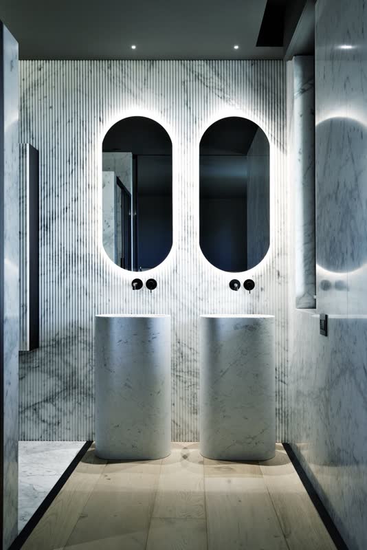 Carrara marble bathroom with twin pedestal washbasins