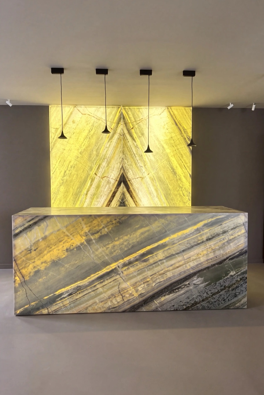 La stessa parete retroilluminata dietro il bancone della reception, con i toni dorati della pietra